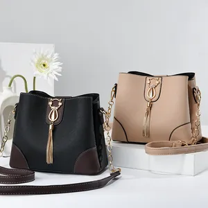 Fashionable cross-pattern leather bucket bags in black and khaki with cat pendants
