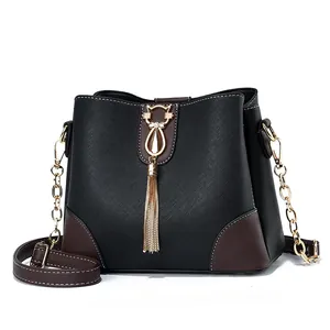 Chic black bucket bag with brown leather trim and golden cat tassel charm detail