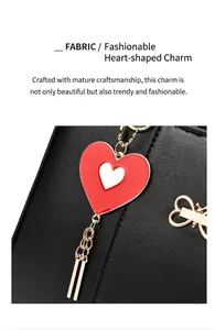 Detailed close-up of a red heart pendant with gold metal edges on black lychee leather bag