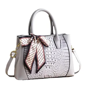Gray crocodile pattern handbag with twin handles and decorative silk scarf detail