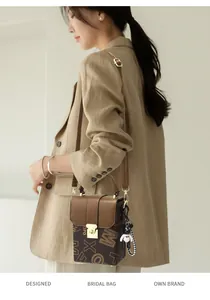 Detail of a brown leather crossbody bag featuring letter prints and a cute bear charm