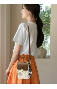 Detailed side view of mini square crossbody bag with brown bear charm and metal buckle