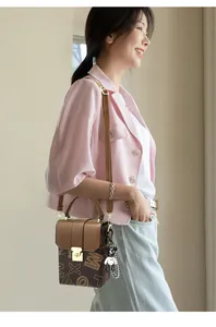 Detail of vintage brown crossbody bag with letter patterns and a golden buckle