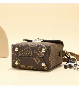 Close-up of brown crossbody bag with letter print and protective gold studs on the bottom