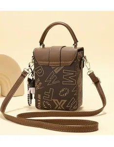 Macro detail of brown leather phone bag with gold hardware and a cute teddy bear charm