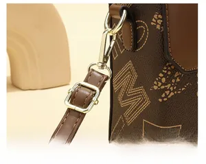 Detail of leather shoulder bag showing golden metal buckle and letter M pattern
