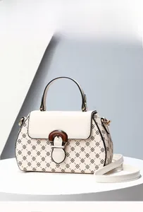 Detail view of the geometric clover print and circular wood-textured buckle on the handbag