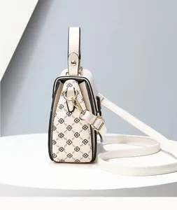 Detail view of cream handbag side profile featuring black clover print and gold hardware