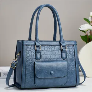 Close-up of grey-blue handbag with crocodile pattern texture and golden hardware details