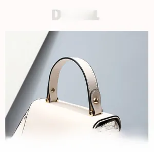 Close-up of white leather handbag handle with woven strap and gold metal rivets