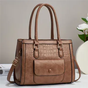 Detailed view of brown crocodile texture leather handbag with dual handles and front pocket