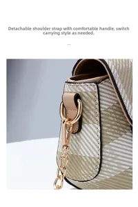 Détail de l'anneau en D doré et de la bandoulière chaîne sur un petit sac à carreaux