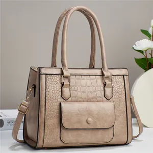 Detail of light brown tote bag featuring crocodile pattern texture and golden hardware
