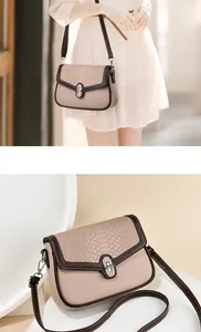 Detail of crossbody bag featuring faux crocodile texture and metallic twist lock closure