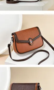 Detail showing brown PU leather crossbody bag with crocodile texture and silver twist lock