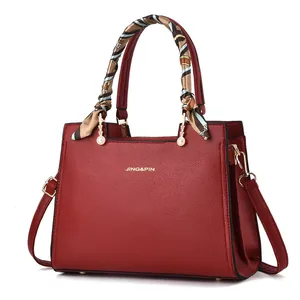 Borsa a mano rossa in pelle con manico a foulard e ciondolo a perla su sfondo bianco