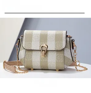 Vue détaillée du sac bandoulière beige à carreaux avec boucle dorée et pieds de sac