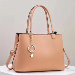 Close-up of litchi pattern leather tote bag with gold smiley face pendant and strap