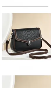 Detail of black crossbody bag with brown snake pattern flap and gold turn-lock closure