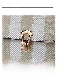 Détail du fermoir doré en forme d'éventail sur le sac à bandoulière beige