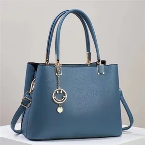 Classic navy blue leather tote bag with gold hardware and stylish charm detail