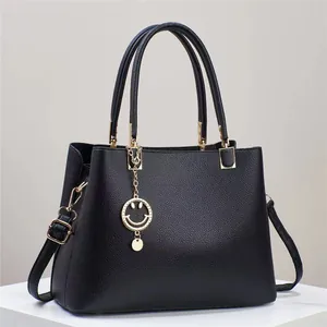 Close-up of black pebble leather tote with gold hardware and smiley face charm detail