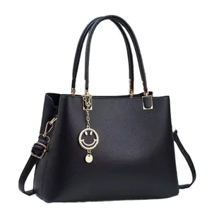 Classic black pebbled leather tote bag with gold chain and smiley face pendant charm