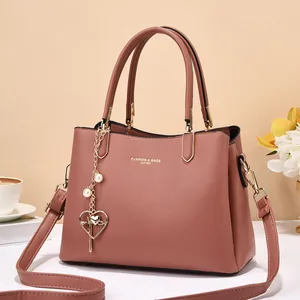 Detail of pink leather handbag with gold hardware, heart pendant and fashion engraving