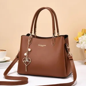 Classic brown leather handbag with adjustable strap and heart pendant accessory