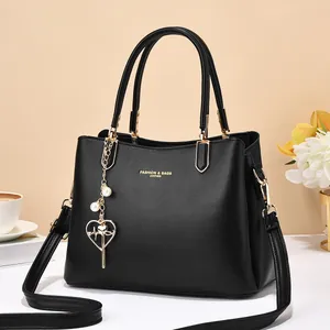 Minimalist black lychee leather handbag with golden hardware and pearl heart charm