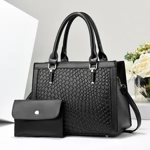 Dettaglio borsa a mano nera in pelle intrecciata con pochette e hardware dorato