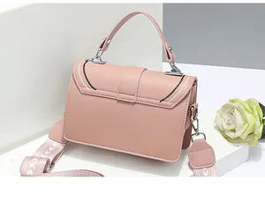 Detailed close-up of pink leather crossbody bag with jacquard strap and silver metal buckles
