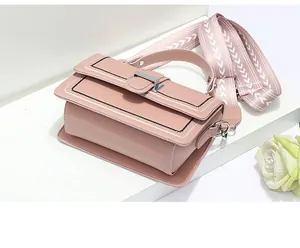 Detail of light pink crossbody bag featuring decorative stitching and silver metal buckle