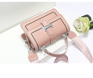Detail of pink crossbody bag with H-buckle, contrast stitching and woven shoulder strap