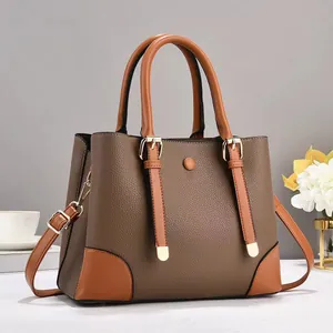 Detail of lychee pattern leather tote bag with dual handles and metal buckle accents