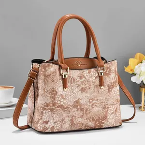 Detail van beige jacquard bloementextuur en bruine lederen bies op een retro handtas