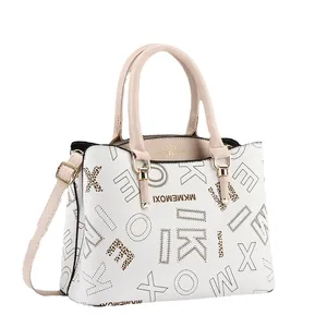 White monogram handbag with pink handles and adjustable strap from a 45-degree angle view