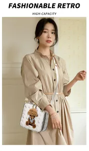 Detail of white square crossbody bag with horse print and plush bear accessory