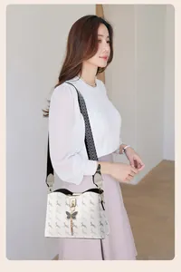 Détail du sac seau imprimé avec pendentif papillon et bandoulière à chevrons