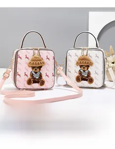 Detail view of bear embroidery on vintage square crossbody bags in pink and white