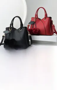 Detail of crossbody bag with cherry pom-pom charm and textured lychee leather finish