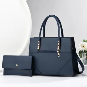 Detail view of deep blue leather tote bag and matching clutch with gold hardware