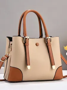 Beige lychee pattern handbag with brown leather trim and gold hardware in studio light