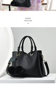 Detail of black litchi pattern leather handbag with plush ball and top handles