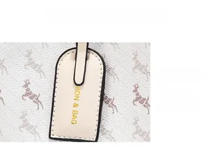 Detail of the delicate cream pendant with golden FASHION & BAG logo on a printed bucket bag