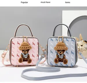 Close-up of bear embroidery and deer print on pink and blue square handbags with gold hardware