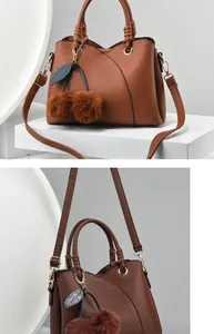 Detail of brown lychee texture handbag with golden hardware and cherry plush charm