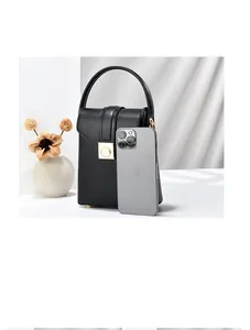 Mini borsa a tracolla in pelle nera con fibbia dorata confrontata a uno smartphone per scala