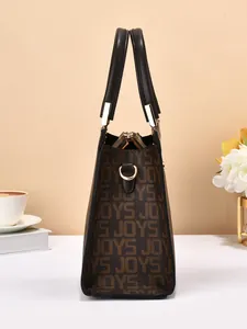 Détail d'un sac à main en cuir marron avec motif monogramme JOYS et boucles dorées