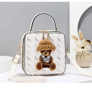 Detail of square white bag with elk prints and a 3D plush bear embroidery ornament